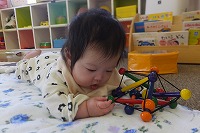 布団の上でオモチャで遊ぶ赤ちゃん