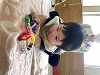 うつ伏せでおもちゃに手を伸ばす６か月