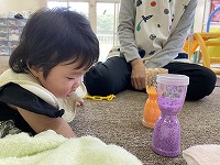 不思議な砂時計のおもちゃをじっと見つめる６か月の女の子