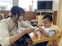 お母さんに離乳食をたせさせてもらう１０ヶ月の女の子