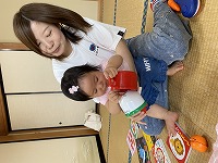 お母さんの膝の上で遊ぶ１歳３カ月の女の子