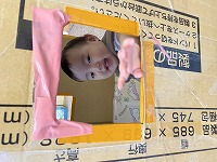 段ボールトンネルの窓から微笑む女の子の赤ちゃん