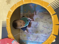 段ボールの窓を見上げて微笑む男の子の赤ちゃん