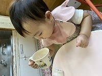 コップを自分で持って飲もうとする女の子の赤ちゃん