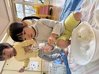 雪をカップに入れて楽しんでいる子ども