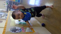 掴まり立ちして手を振る男の赤ちゃん
