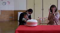 ケーキのぬいぐるみにイチゴを飾る子ども