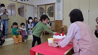 ケーキのぬいぐるみにイチゴを飾る子ども