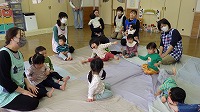 大きな布に座って喜ぶ子ども達